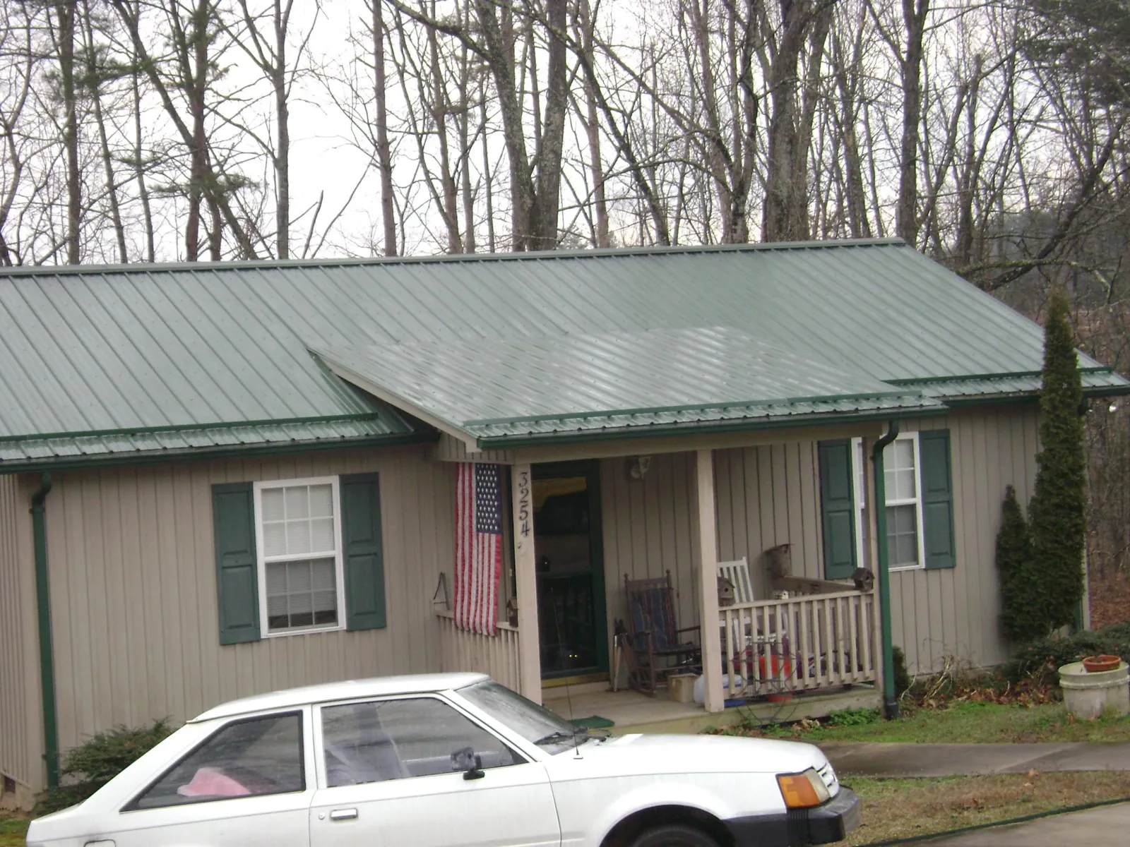 Green metal roof and front porch on a tan sided cottage in Centerville